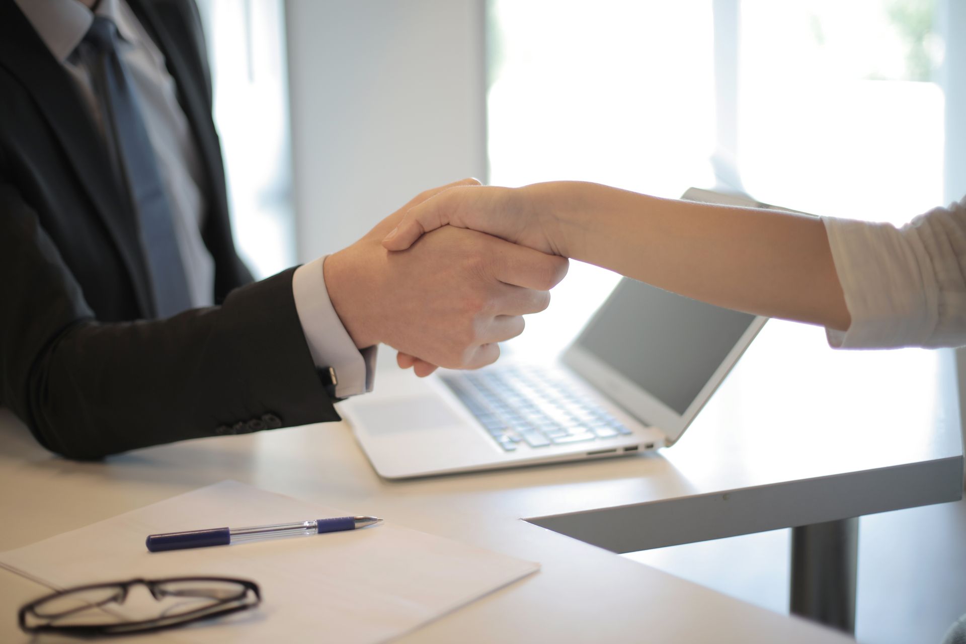 Hiring manager shaking hands with a new employee in a modern office