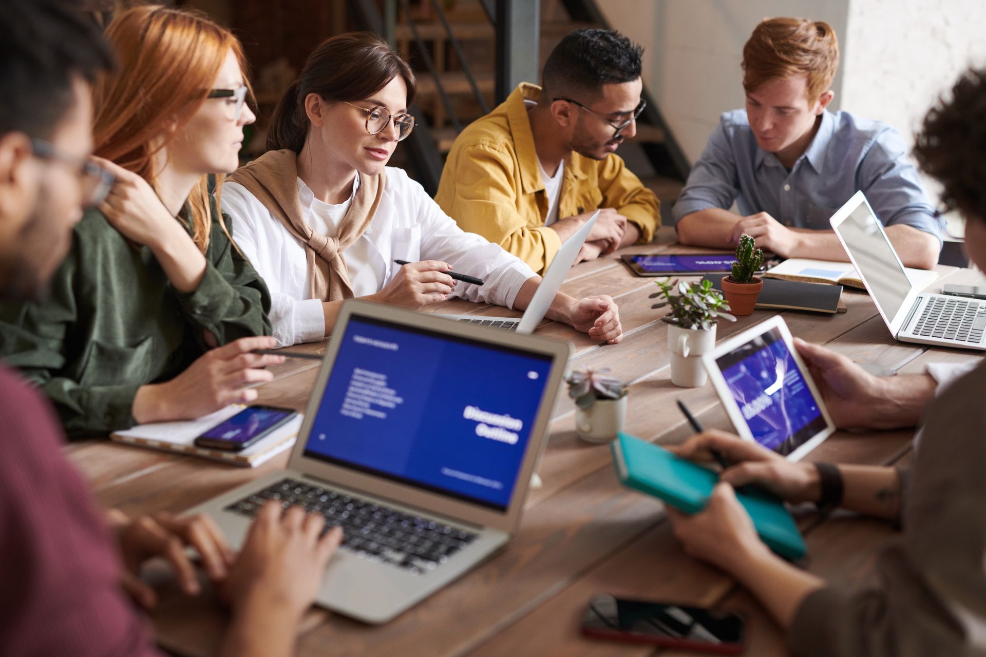 Diverse team of AI professionals collaborating around a laptop in a bright modern office
